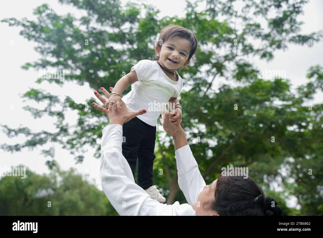 Beautiful Young indian mom throwing baby girl up in air and catching