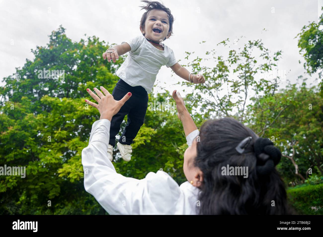 Beautiful Young indian mom throwing baby girl up in air and catching