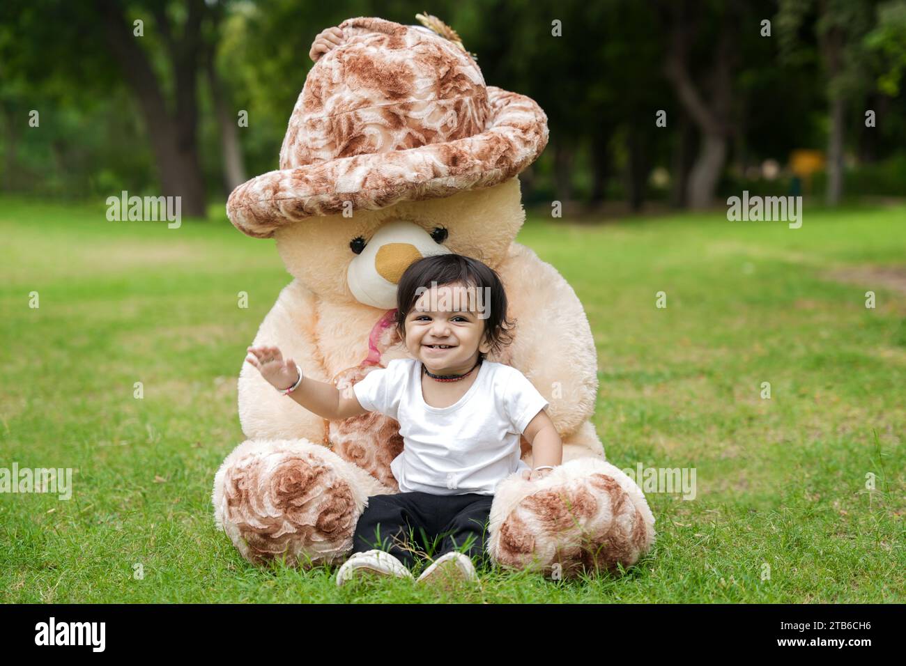 Teddy Playing Cute little Boy sitting and playing with huge teddy bear at park or ...