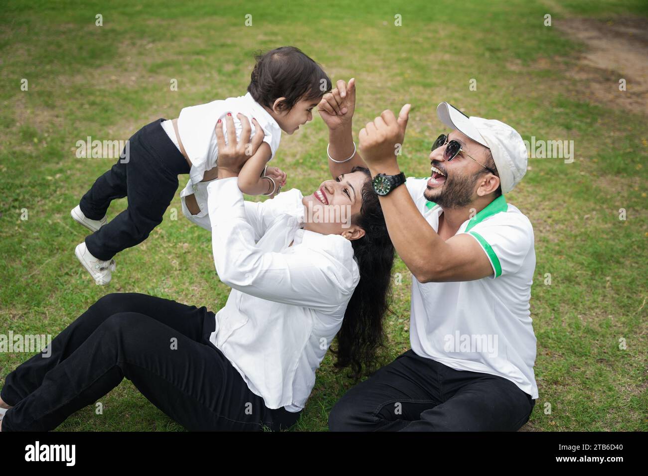 Young indian family of three mom throwing baby girl up in air and dad