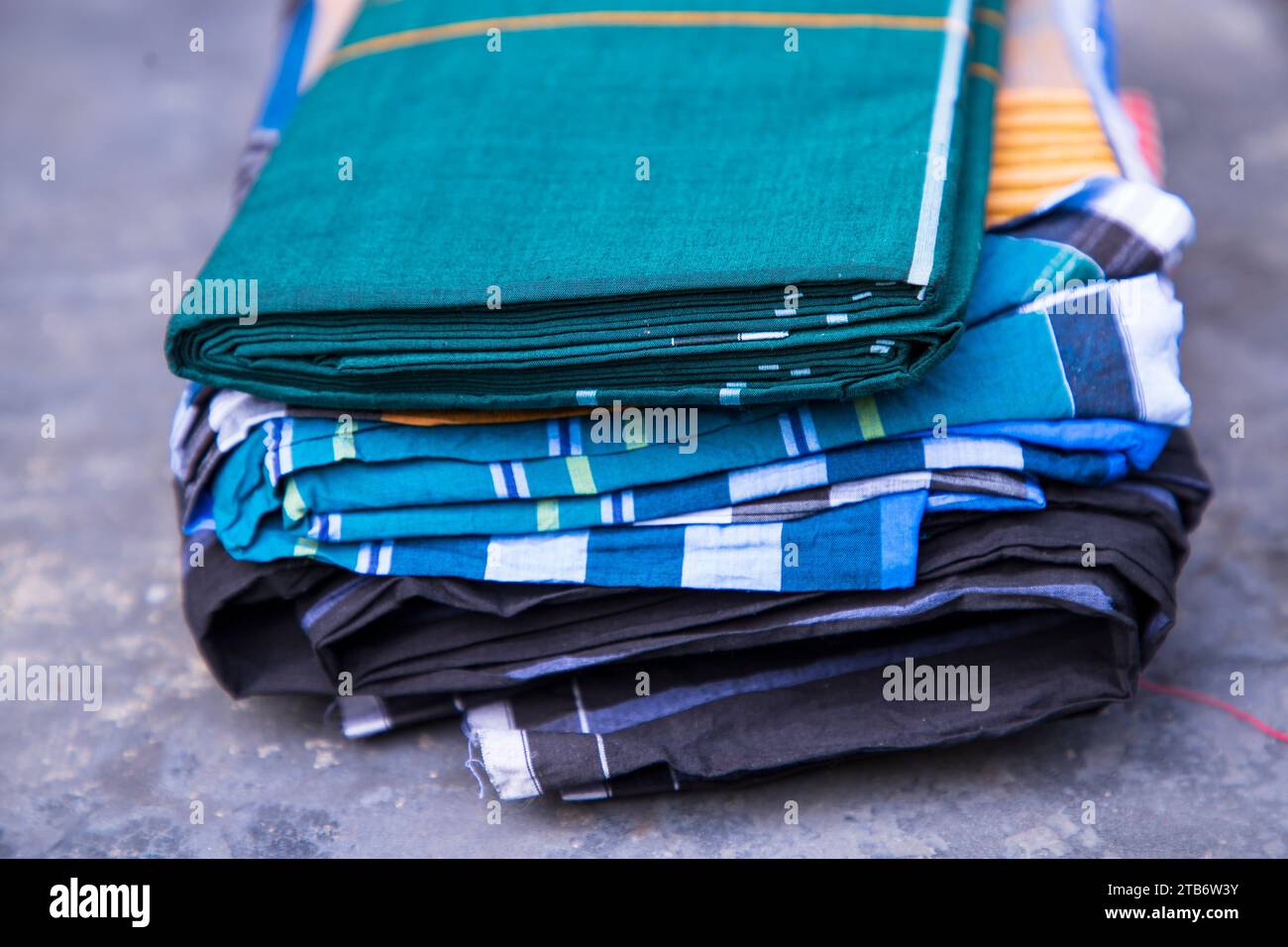 Folded Cotton Fabric Lungi on dark Concrete floor Traditional Men's Fashion Lifestyle in Bangladesh. Selective Focus Stock Photo