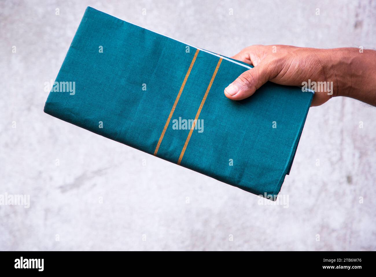 Folded Cotton Fabric Lungi hand holding with gray Background. Traditional Men's Fashion Lifestyle in Bangladesh Stock Photo