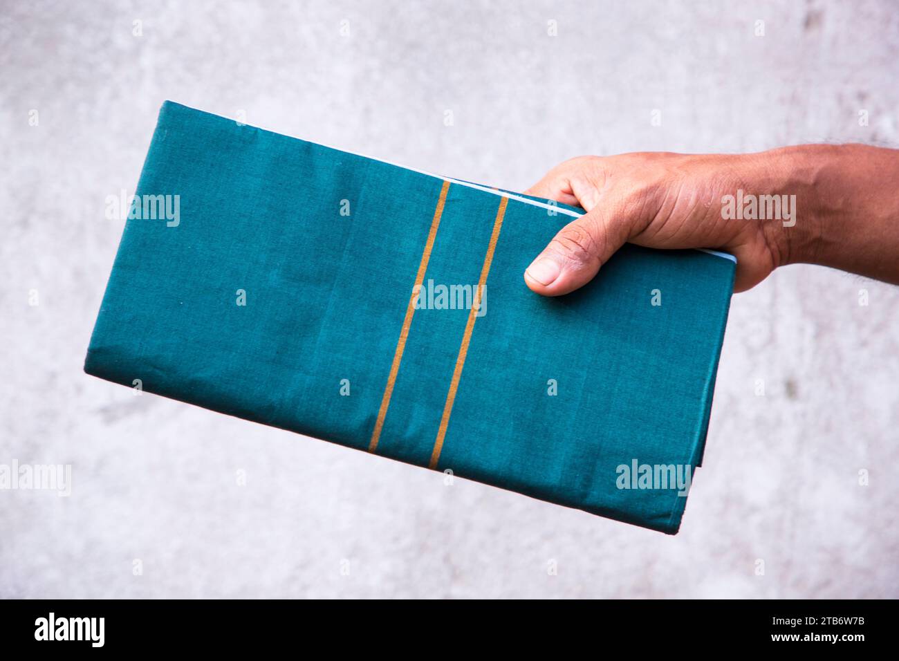 Folded Cotton Fabric Lungi hand holding with gray Background. Traditional Men's Fashion Lifestyle in Bangladesh Stock Photo