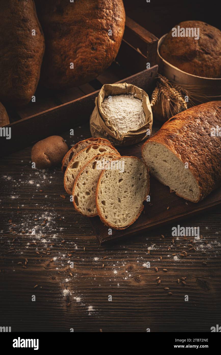 Artisanal sliced bread loaves on dark wooden background Stock Photo