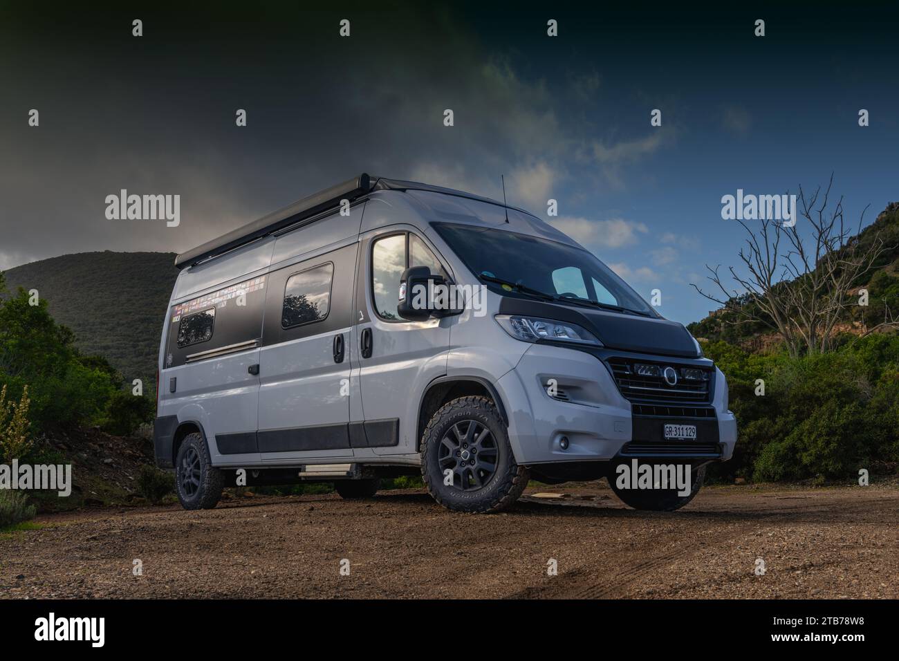 A low angle view of a gray campervan parked on a red dirt road Stock Photo
