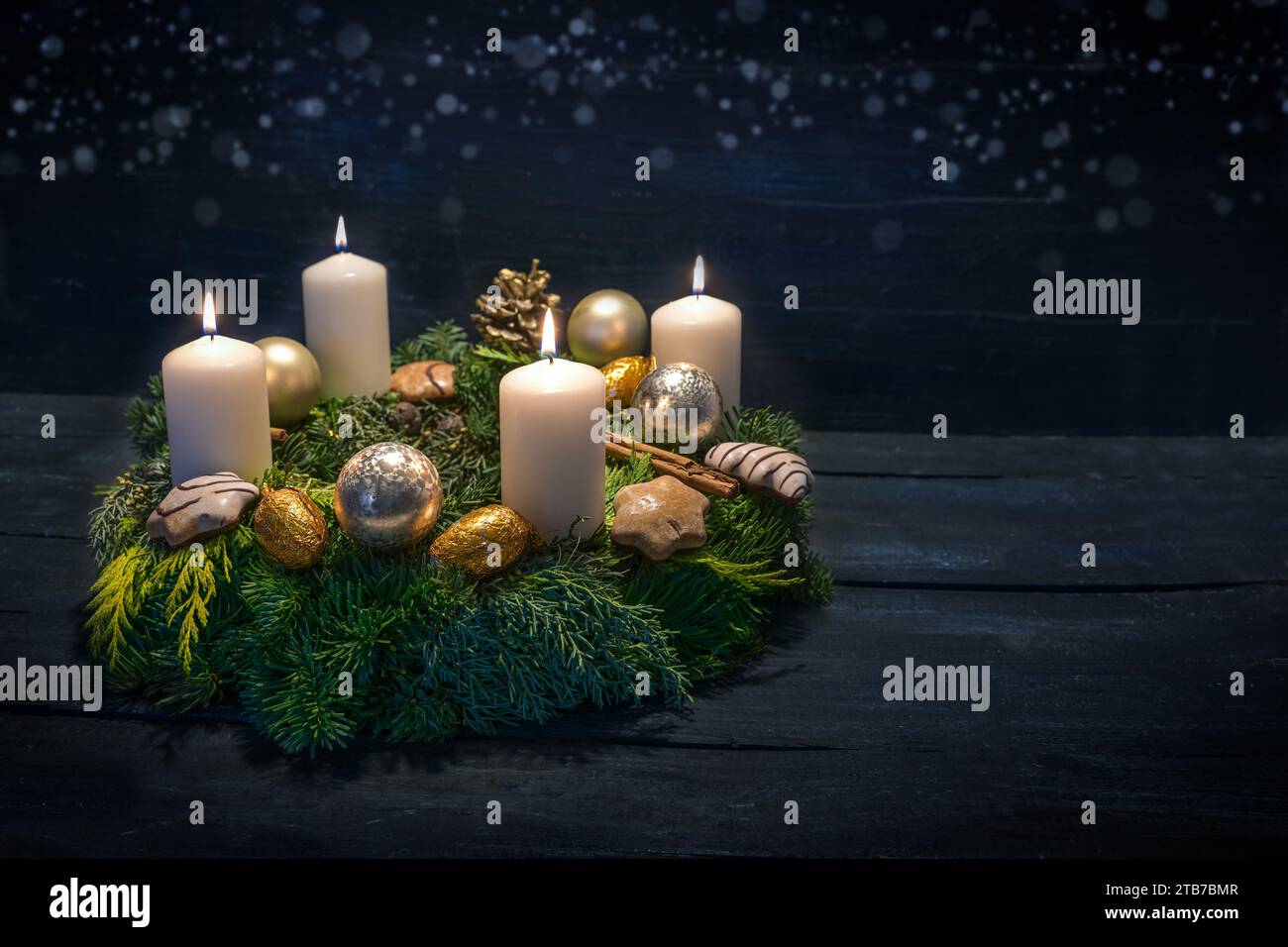 Green advent wreath with white candles, four are lit for fourth advent, Christmas decoration and cookies, dark blue wooden background with star bokeh, Stock Photo