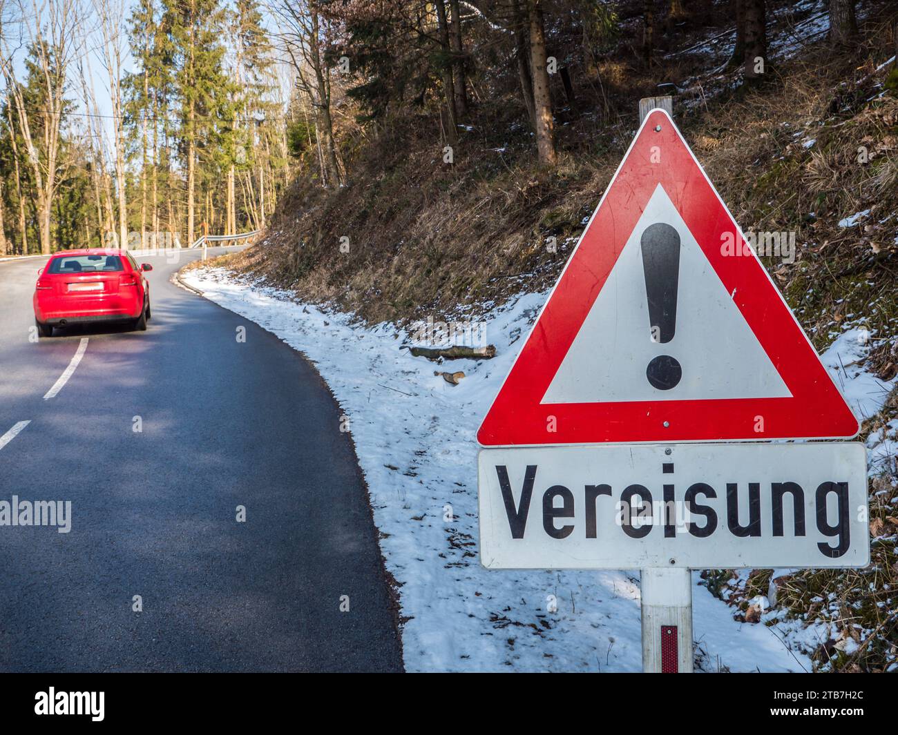 Red warning sign about icing of the road in winter in German Stock Photo