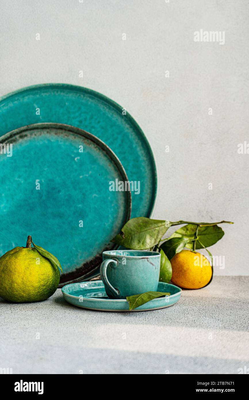 A beautifully arranged table setting in turquoise tones, complemented by fresh citrus fruits, creating an inviting dining atmosphere. Stock Photo