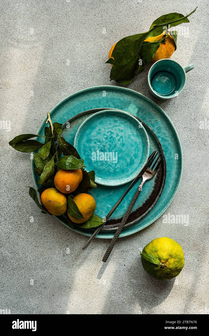 A striking composition featuring ripe tangerine with leaves on an aqua-hued ceramic plate, adding a touch of natural freshness. Stock Photo