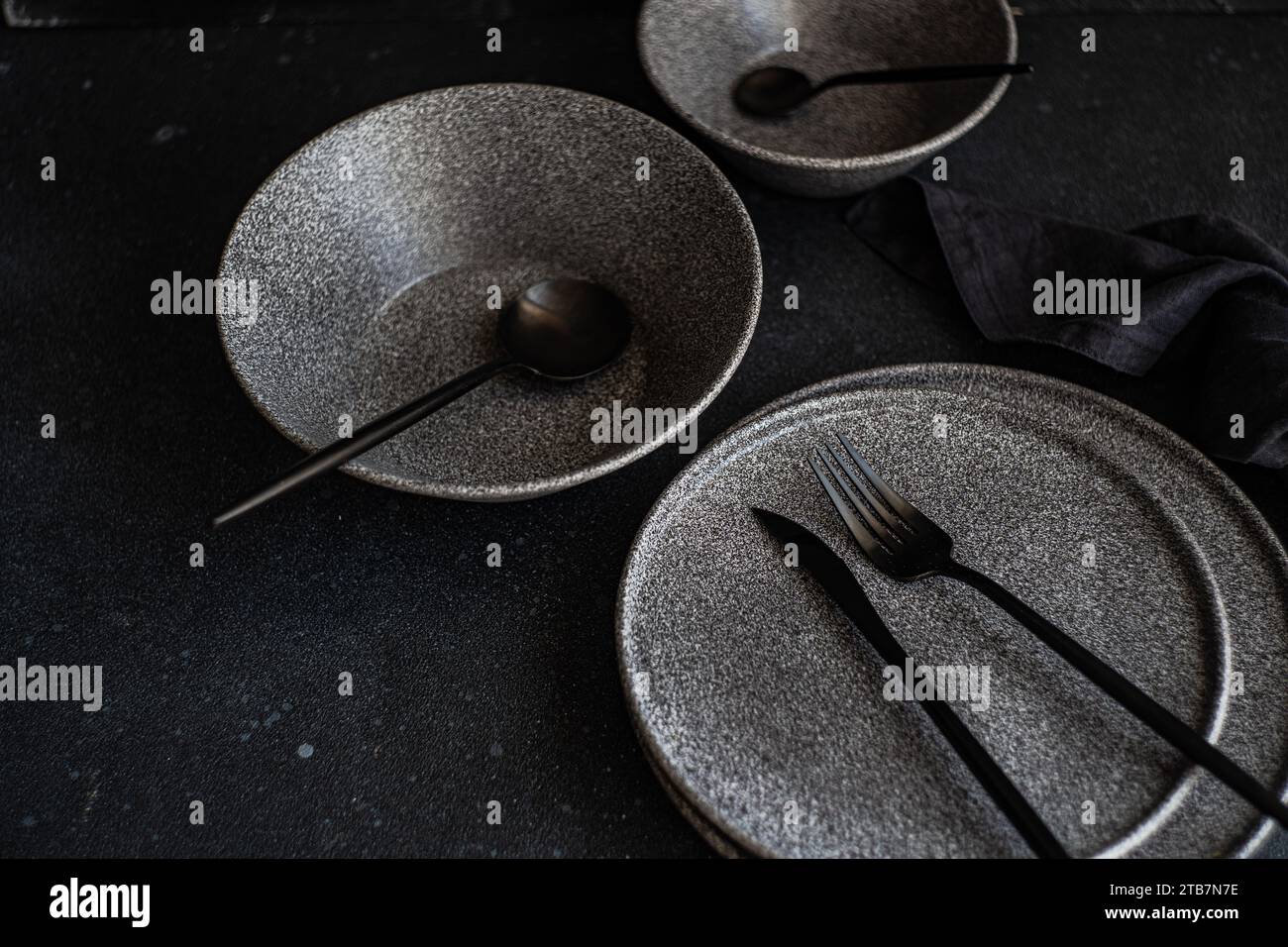 An elegant arrangement of dark stoneware dishes with sleek utensils