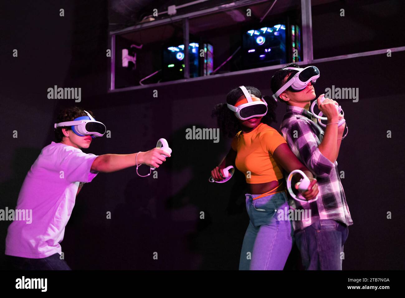 Exited multiracial friends enjoying a virtual reality game, each ...