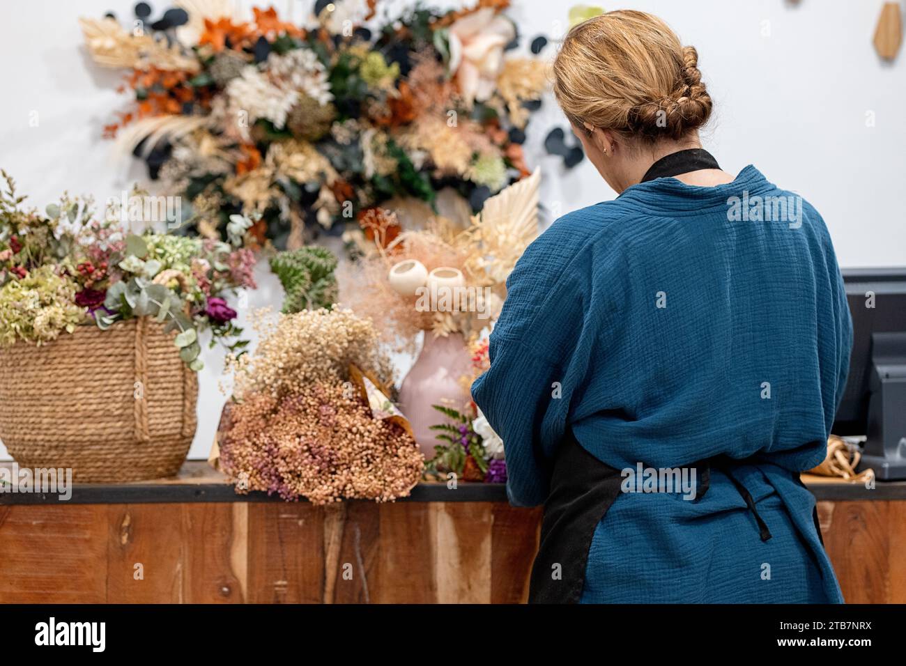 Back view of unrecognizable skilled florist is carefully arranging a selection of colorful dried flowers workshop Stock Photo