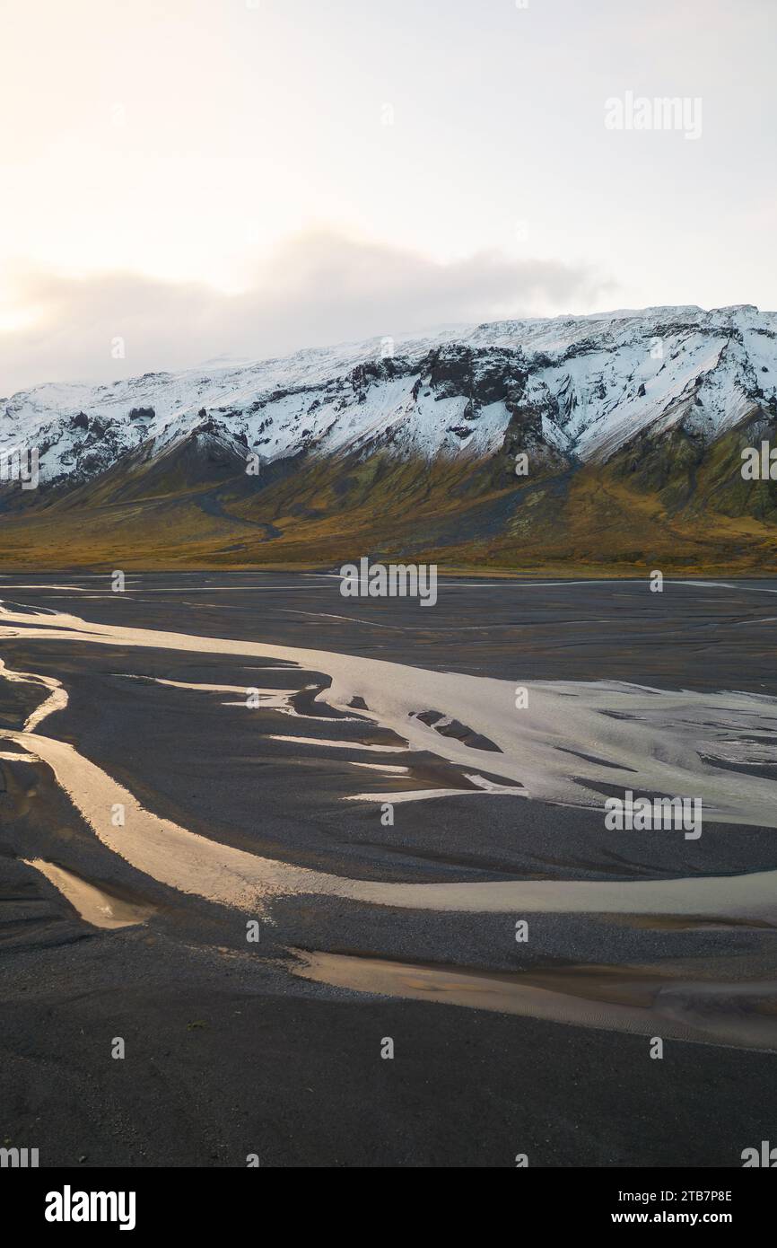 View of a winding river with a backdrop of snow covered mountains during golden hour in Thorsmork Valley Iceland Stock Photo