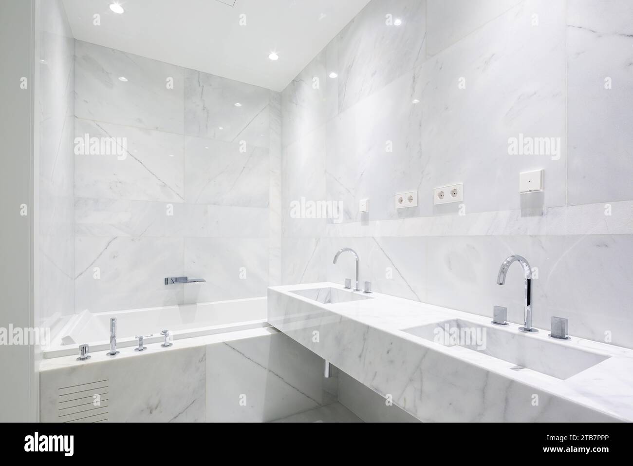 View of Interior of stylish illuminated bathroom with ceramic bathtub and ...