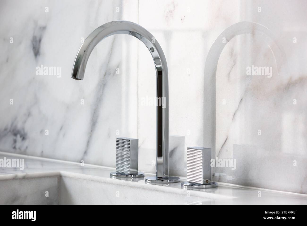 Image showcasing Closeup of sink with stainless steel faucet against white marble wall ...