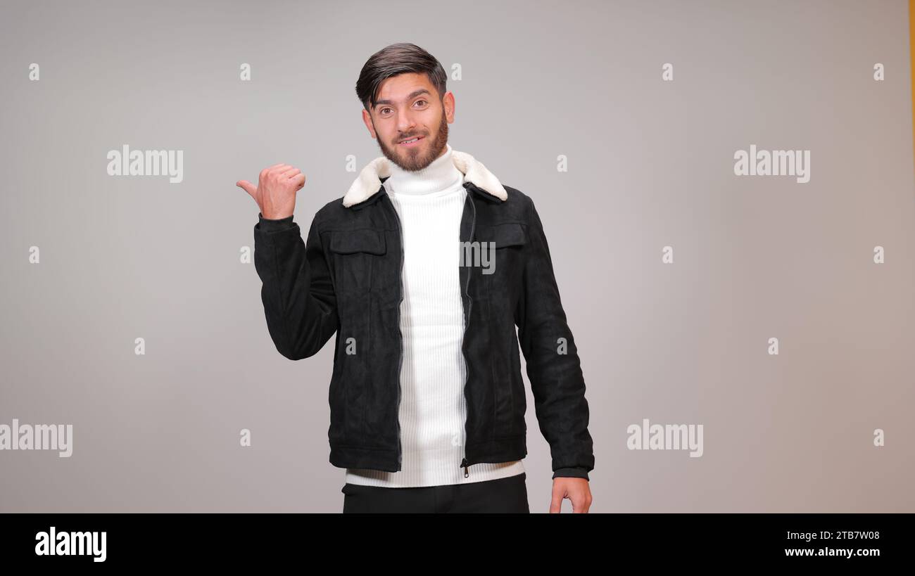A young man striking a surprised pose against a gray background. Stock Photo