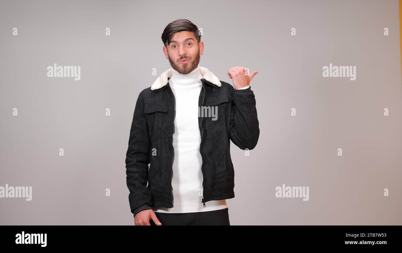 A young man striking a surprised pose against a gray background. Stock Photo