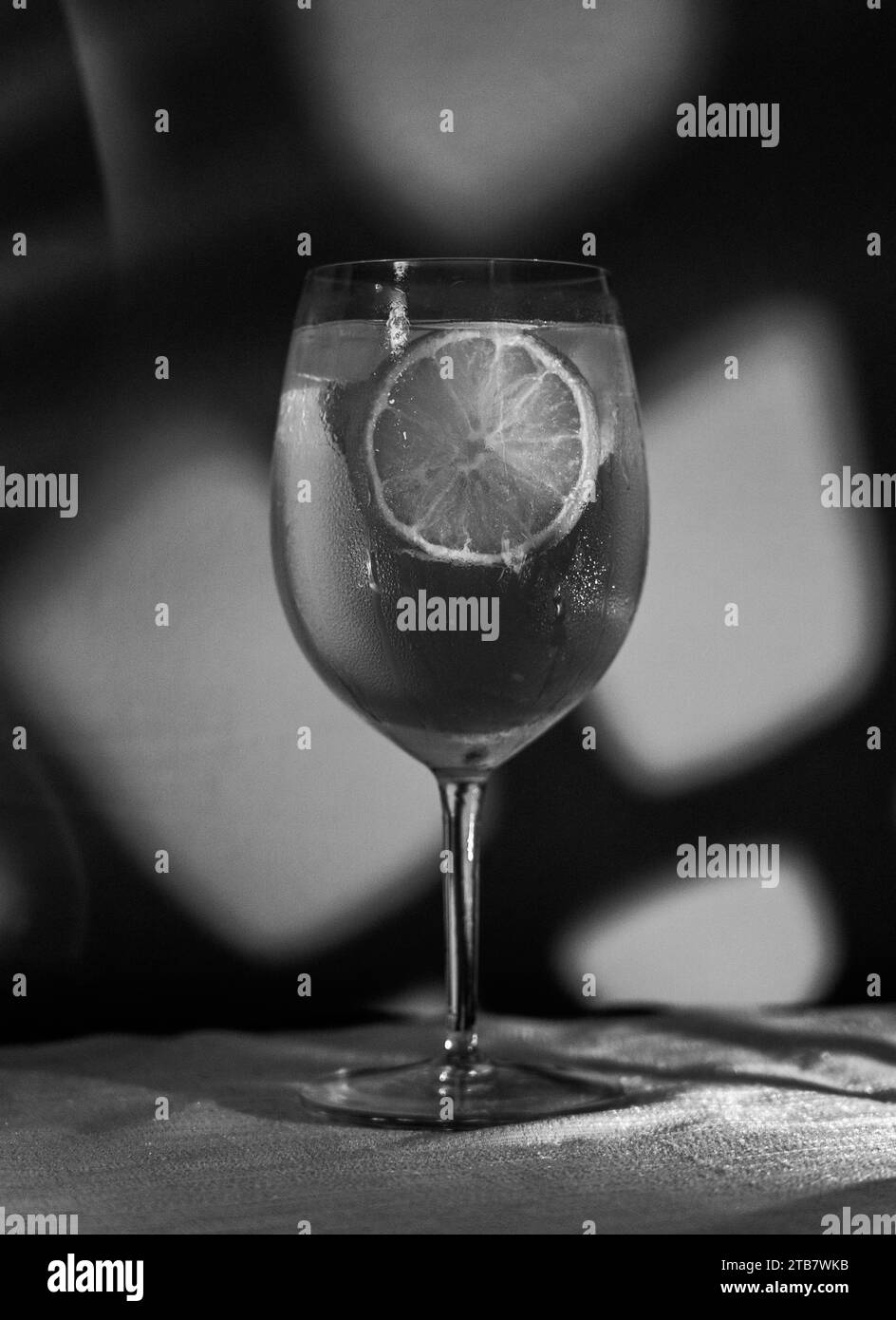 Gin and tonic cocktail with ice and lemon slices in black and white, noir style Stock Photo