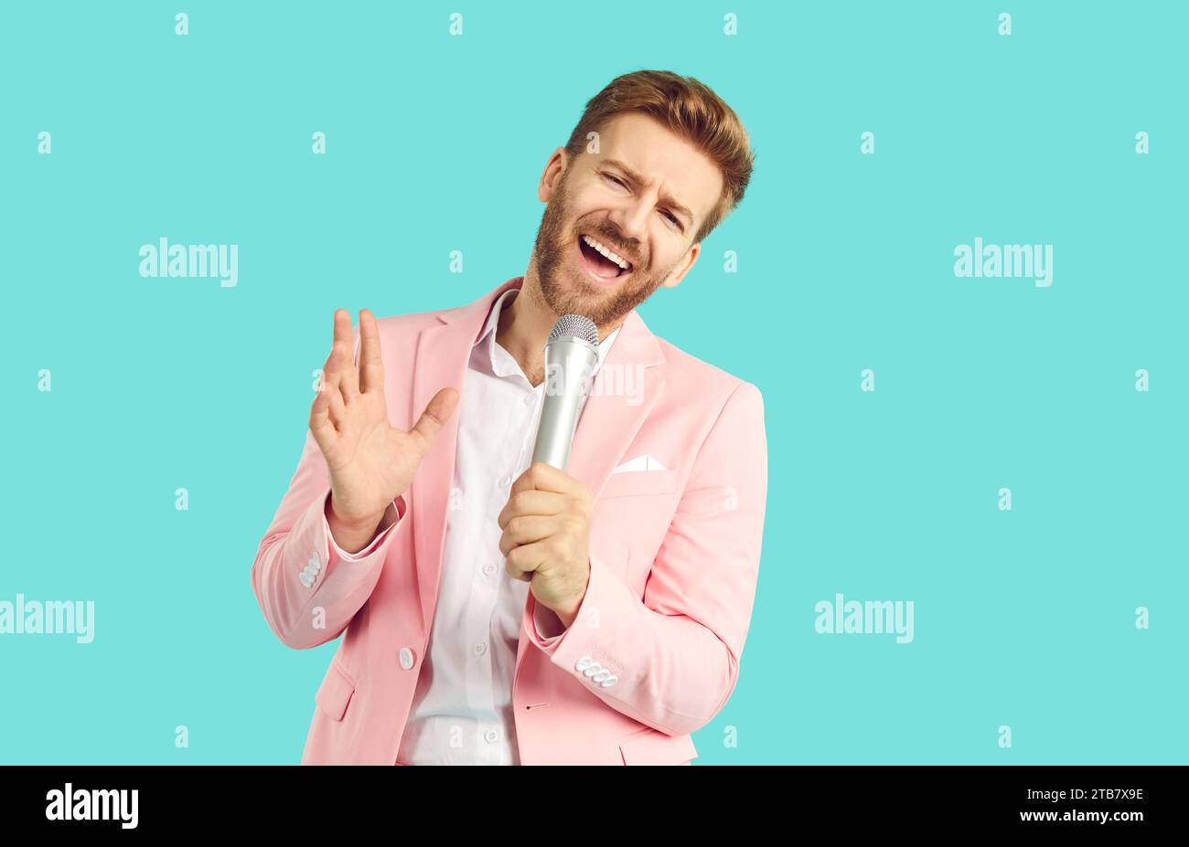 Handsome emotional young man singing over microphone and gesturing Stock Photo