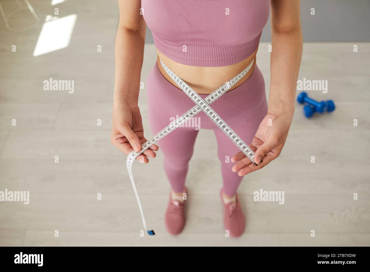 Slim young woman with athletic body is measuring her figure with tape measure. Stock Photo