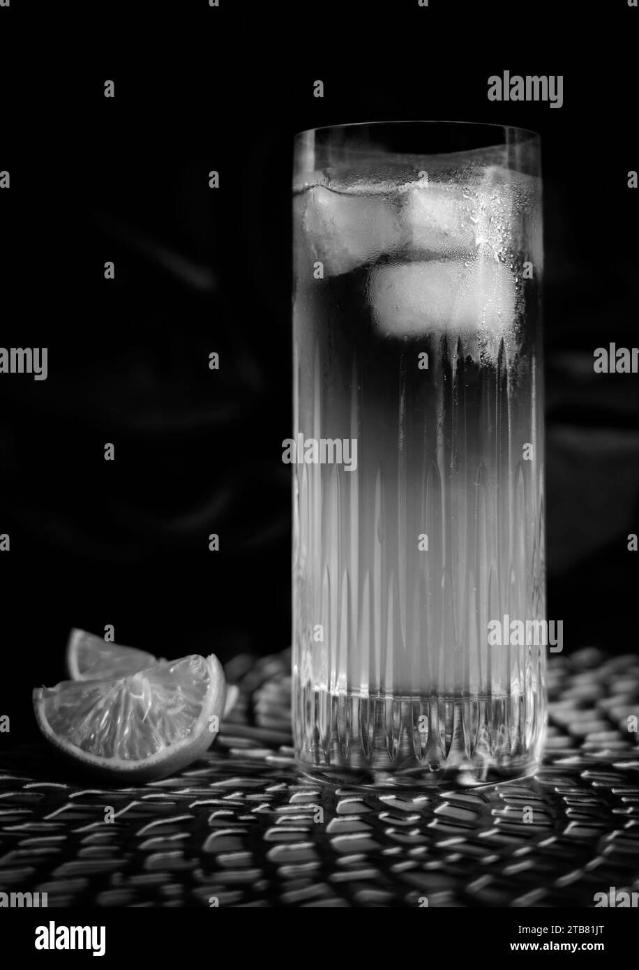 Dark and Stormy cocktail in black and white with ice and lemon in high ball glass Stock Photo