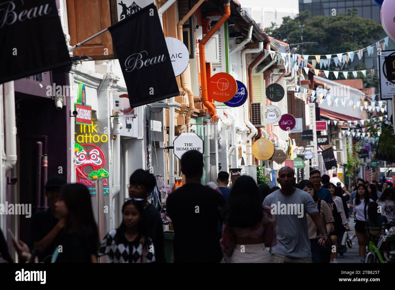Buzzing with people at Haji Lane, the scene is divided into light and shadow creating a mystery silhouette effect of the people. Singapore. Stock Photo