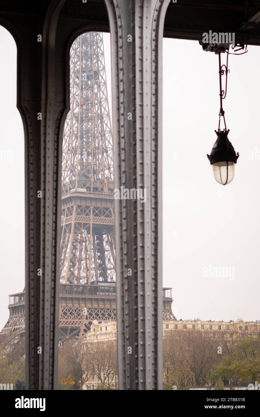The Eiffel Tower between the pillars of the Bir Hakeim bridge in Paris on a cloudy cold winter day - France Stock Photo