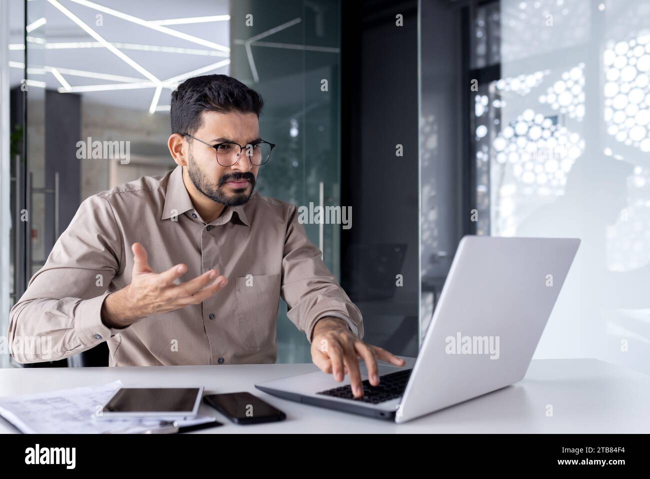 Idle computer, broken laptop at workplace, unhappy angry businessman at workplace shouting unhappy with slow software. Stock Photo