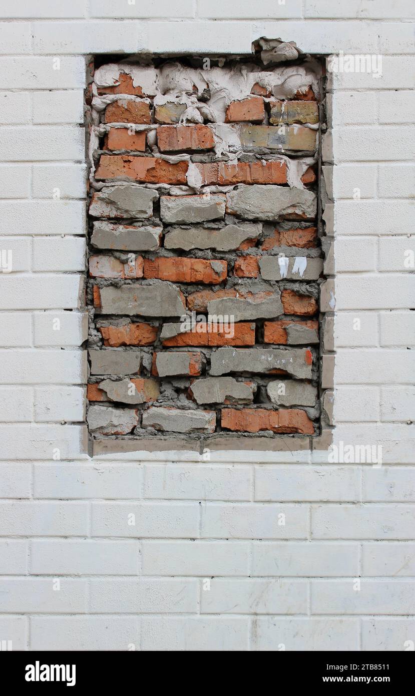 A clean white wall with an unpainted bricked window vertical stock