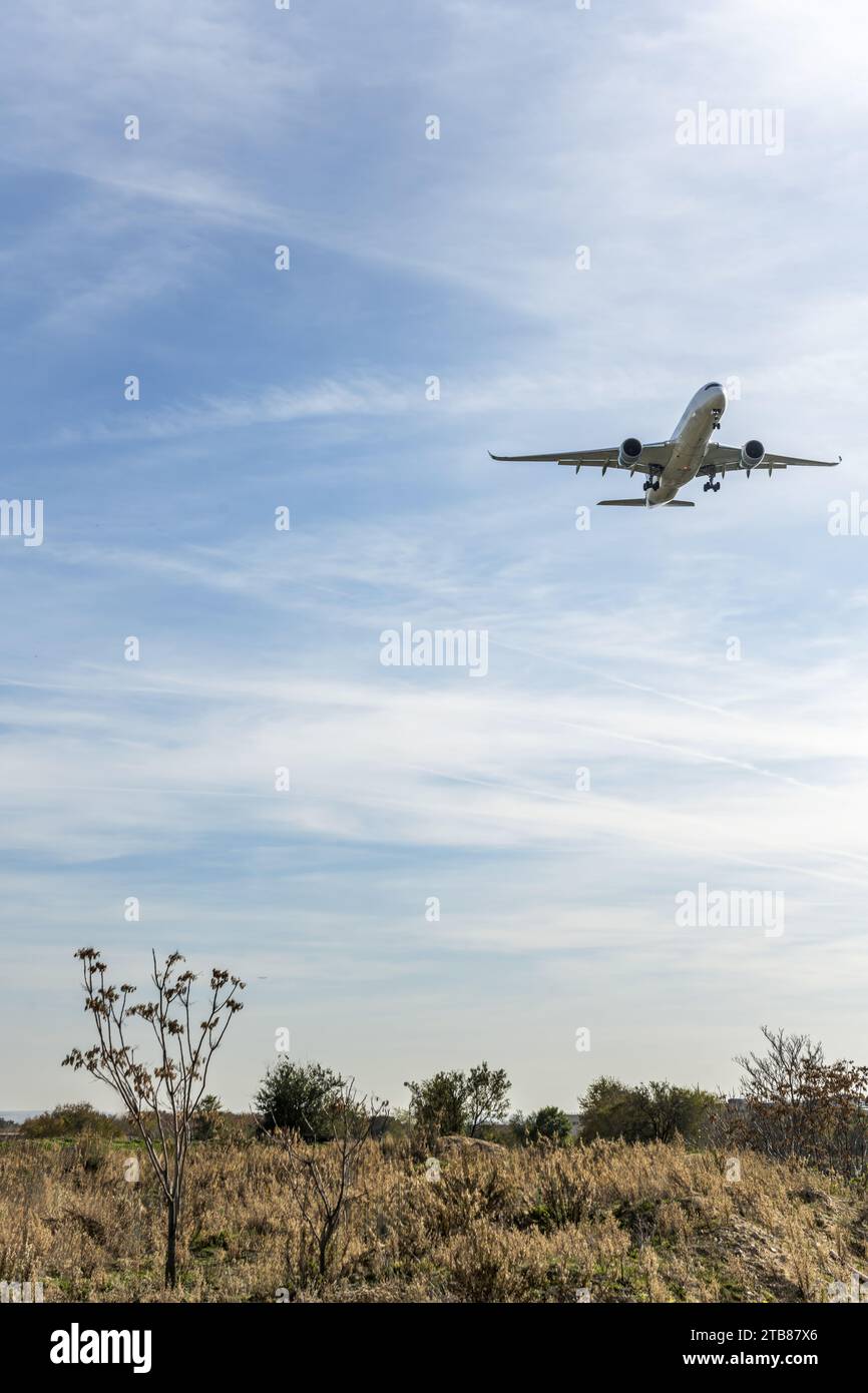A commercial airplane flying low near the field Stock Photo