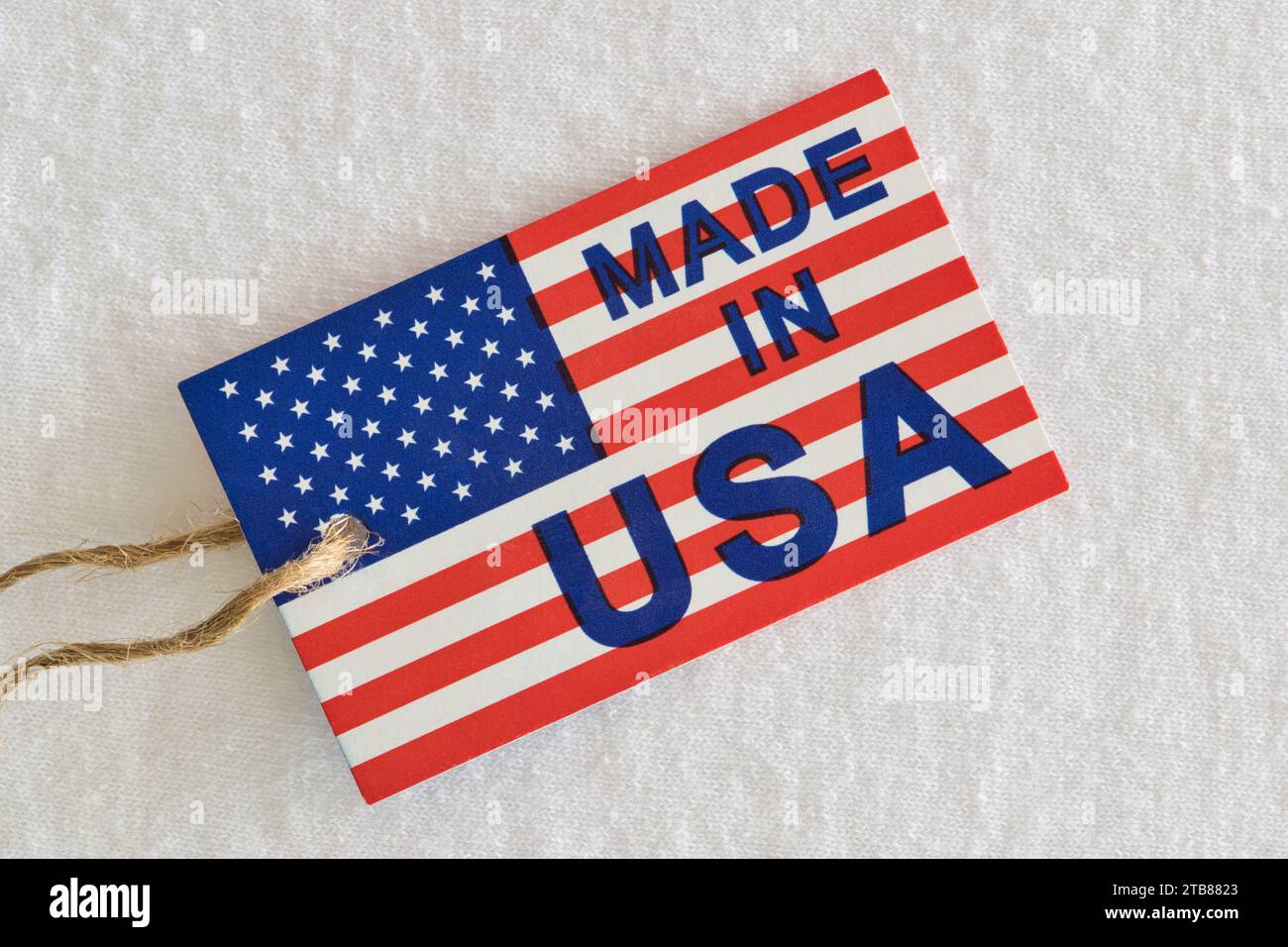 Made in USA label sitting on top of white clothing as a business economics concept. Flat lay macro image with patriotic background details. Stock Photo