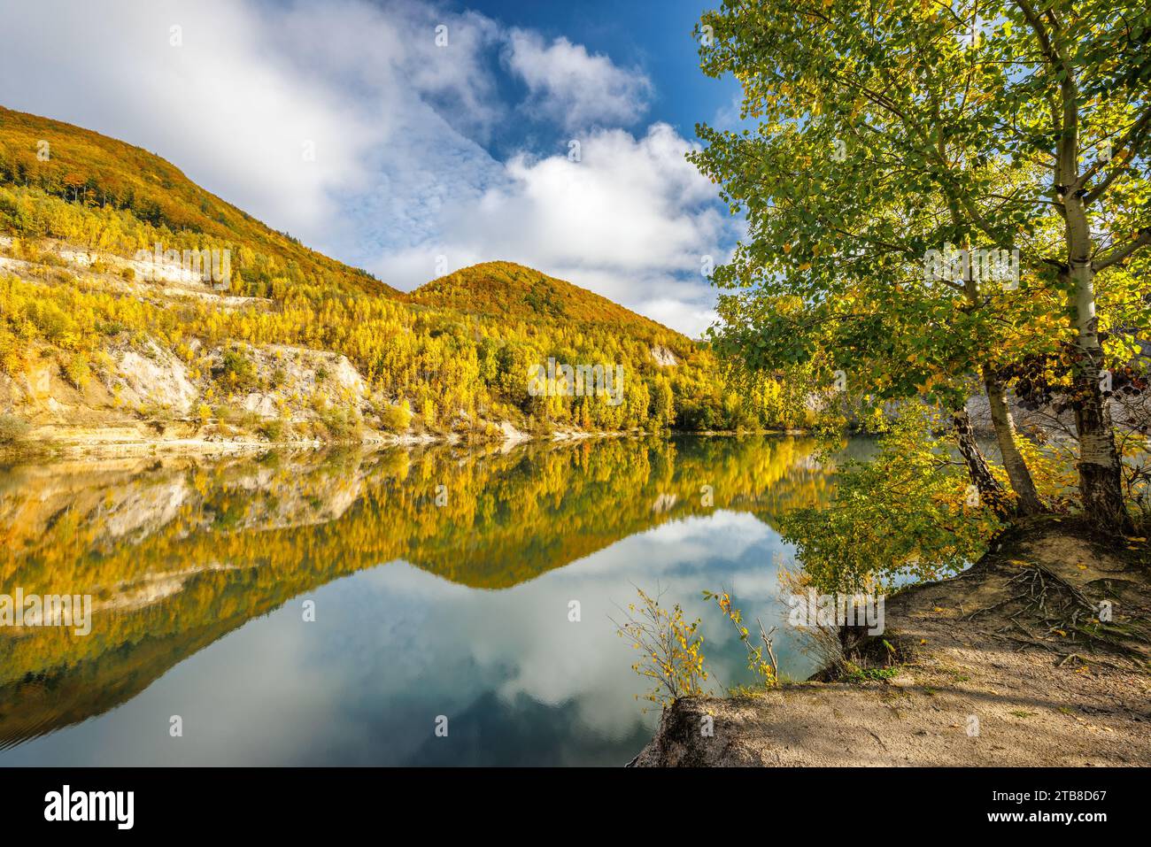 Autumn landscape with reflection of colorfull hills in the lake. Flooded quarry near the village Sutovo in Slovakia, Europe. Stock Photo