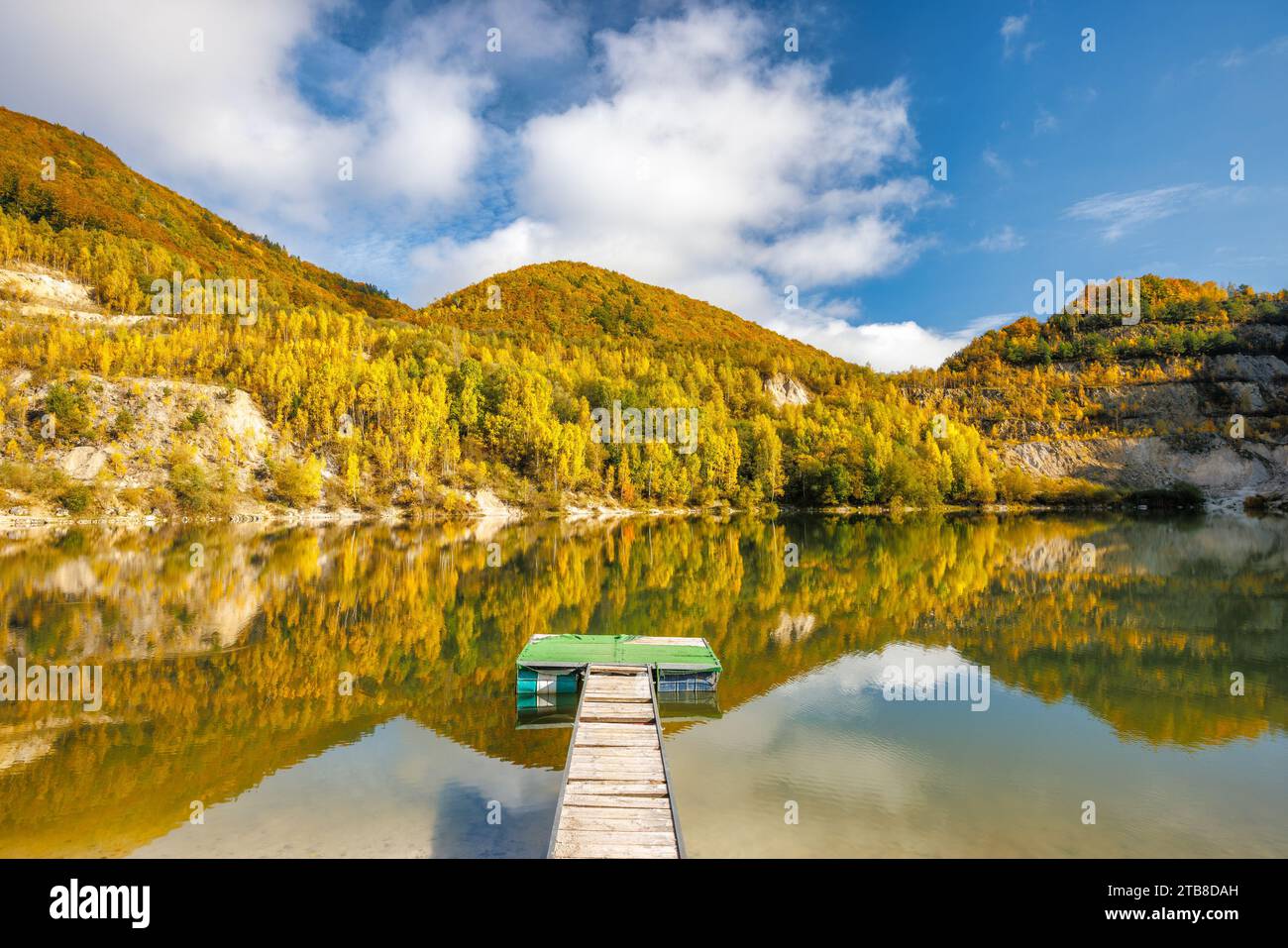 Autumn landscape with reflection of colorfull hills in the lake with boarding pillar. Flooded quarry near the village Sutovo in Slovakia, Europe. Stock Photo