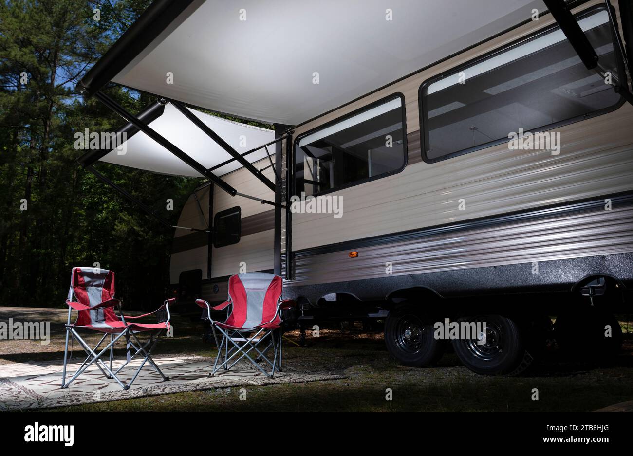 Camping trailer set up in a forested campground with awnings out and