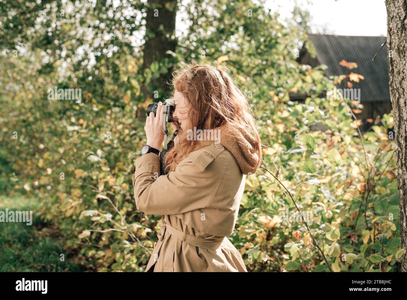 red-haired girl in a beige trench coat in autumn Stock Photo