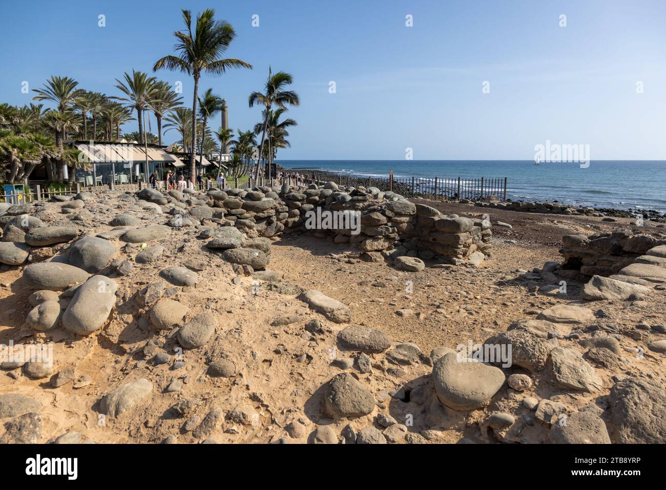 Gran Canaria, Spain - November 23, 2023: Maspalomas  Lighthouse in Gran Canaria, spain,  at the promenade with tourists and the Punta Mujeres Archaeol Stock Photo
