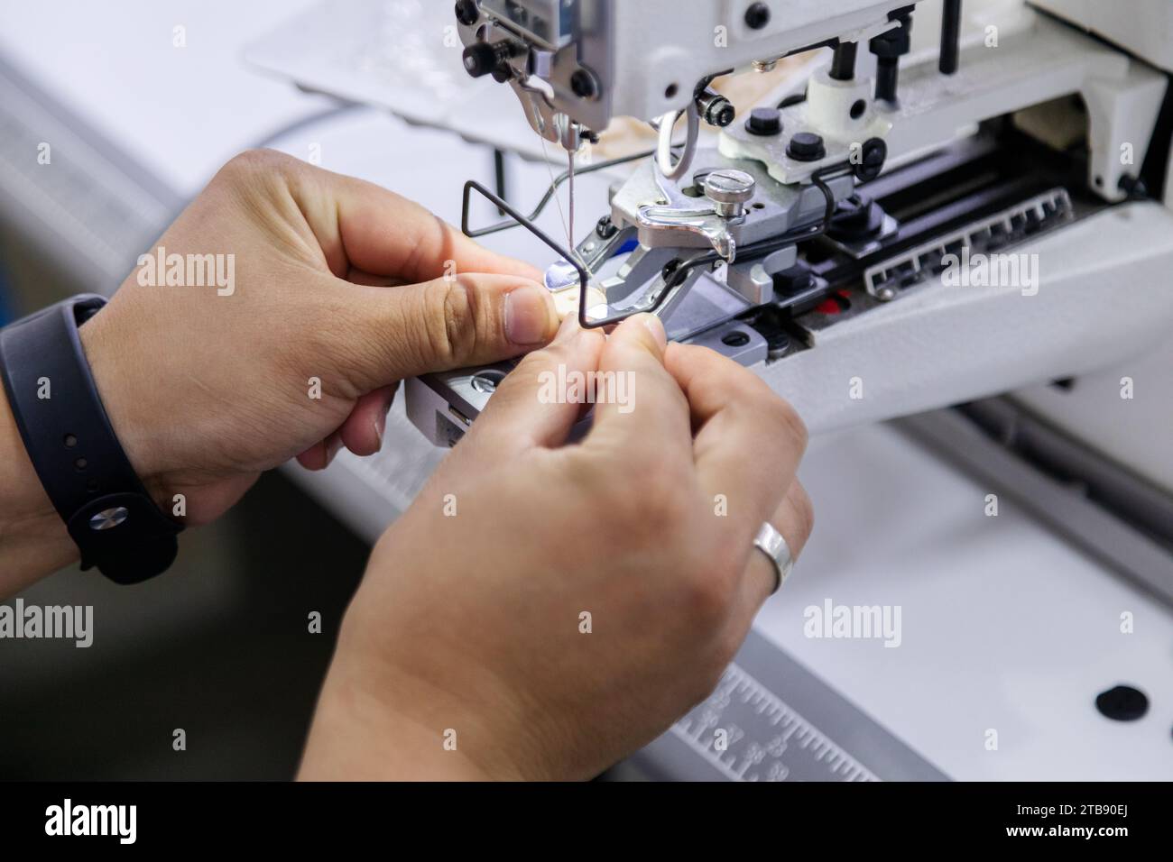 Close up of tailor adding button to electric sewing machine Stock Photo