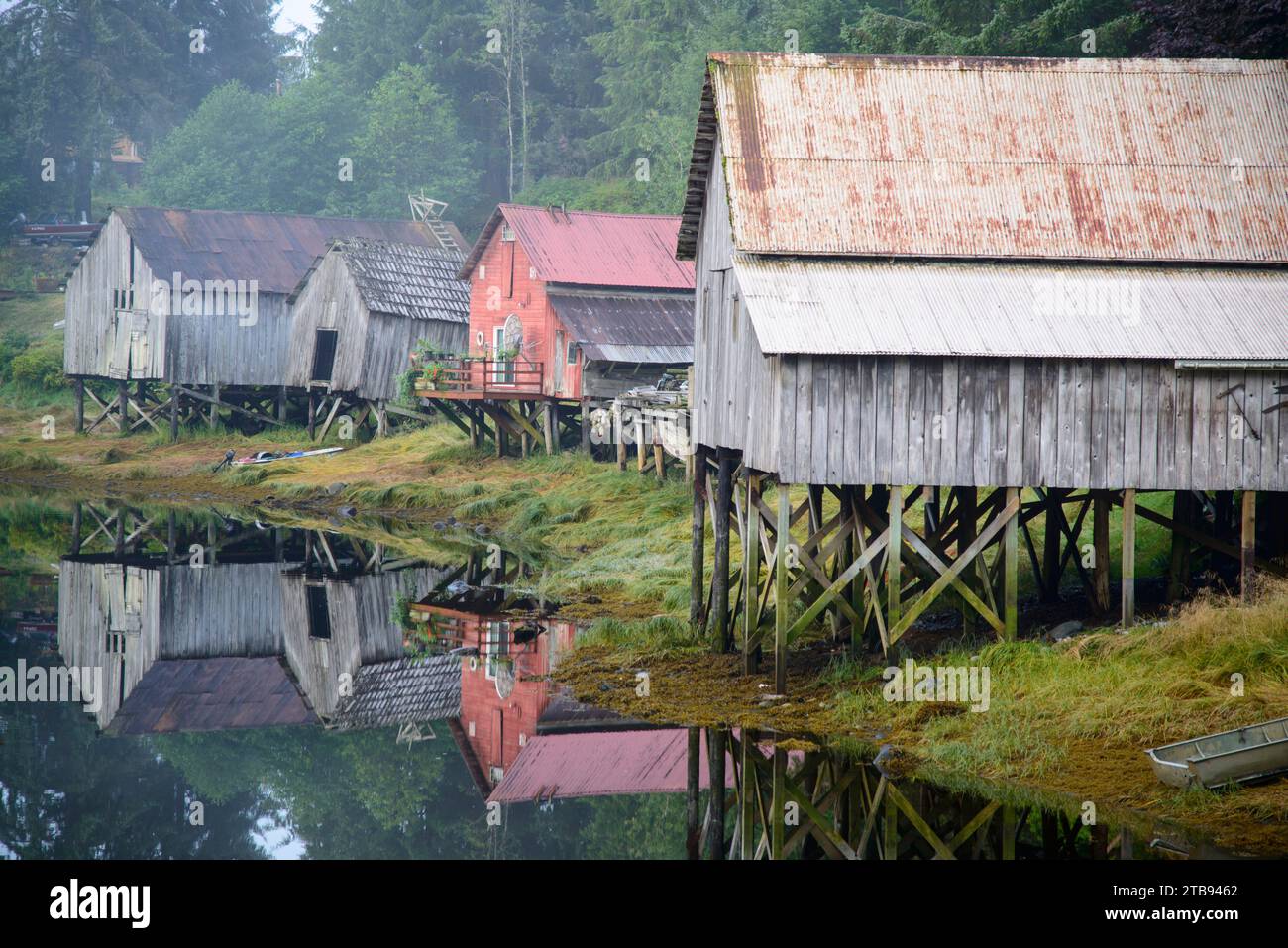 Old wooden boat houses on stilts reflected in water; Petersburg, Alaska