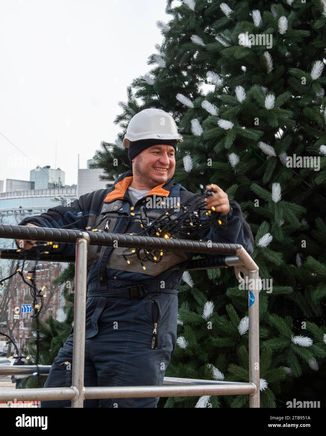 2023-12-05 Kyiv, Ukraine. Smiling worker man preparing Christmas lights for the Christmas tree decoration Stock Photo