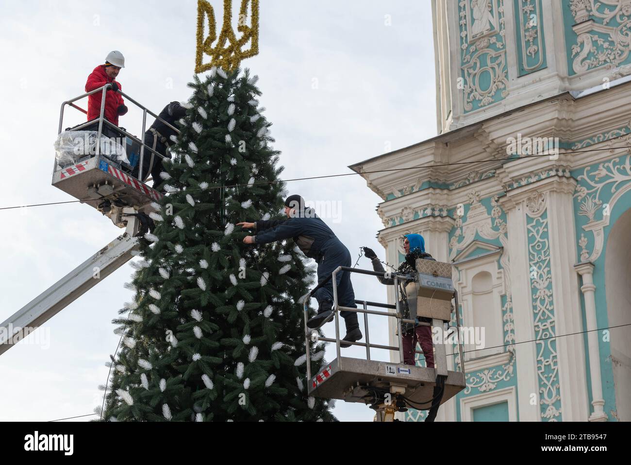 2023-12-05 Kyiv, Ukraine. Men decorating the Christmas tree with glowing garlands using car towers Stock Photo