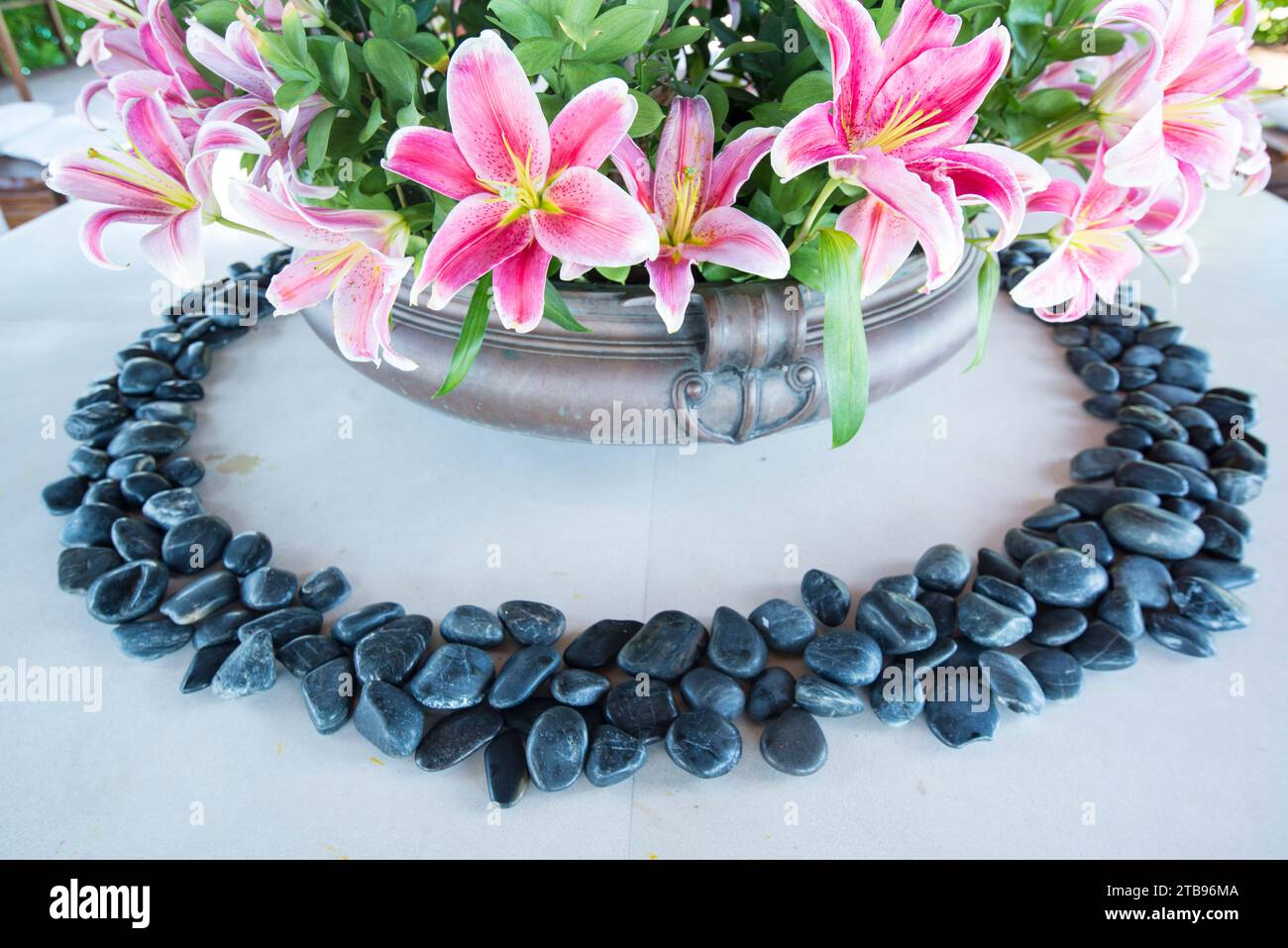 Polished black stones ring a bouquet of pink lilies; Republic of the Maldives Stock Photo