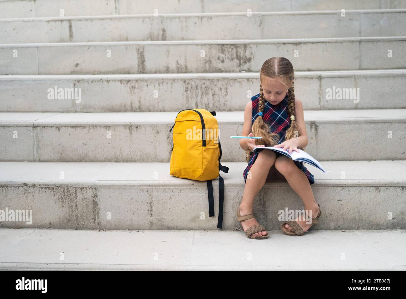 Backpack With Homework schoolgirl, backpack nearby, concentrates on her homework, jotting ...