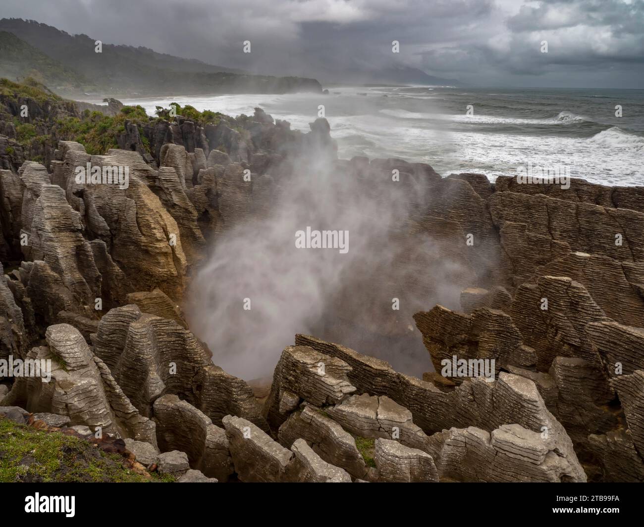 High tide and a strong swell produce a blast of ocean mist at a rocky blowhole; Greymouth, Punakaiki, South Island, New Zealand Stock Photo