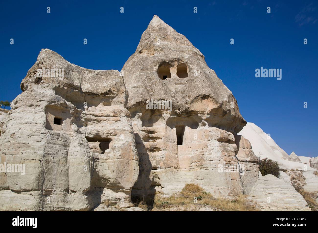Close-up of a rock house carved into the volcanic rock formations, a Fairy Chimney, against a bright blue sky near the Town of Goreme in Pigeon Val... Stock Photo