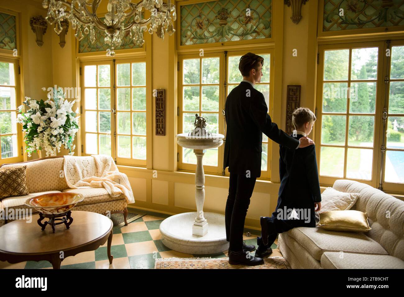Young man and young boy in formalwear look out the window together; Lincoln, Nebraska, United States of America Stock Photo