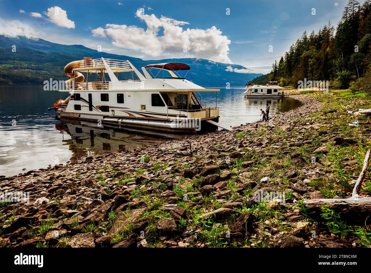 A family enjoying a houseboat vacation while parked on the shoreline of ...