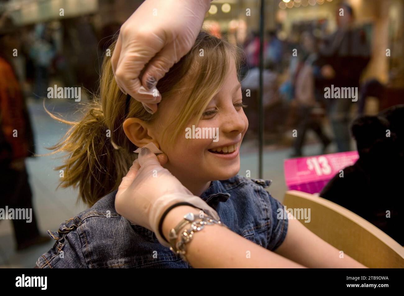 Young girl gets her ears pierced at a mall; Lincoln, Nebraska, United States of America Stock Photo