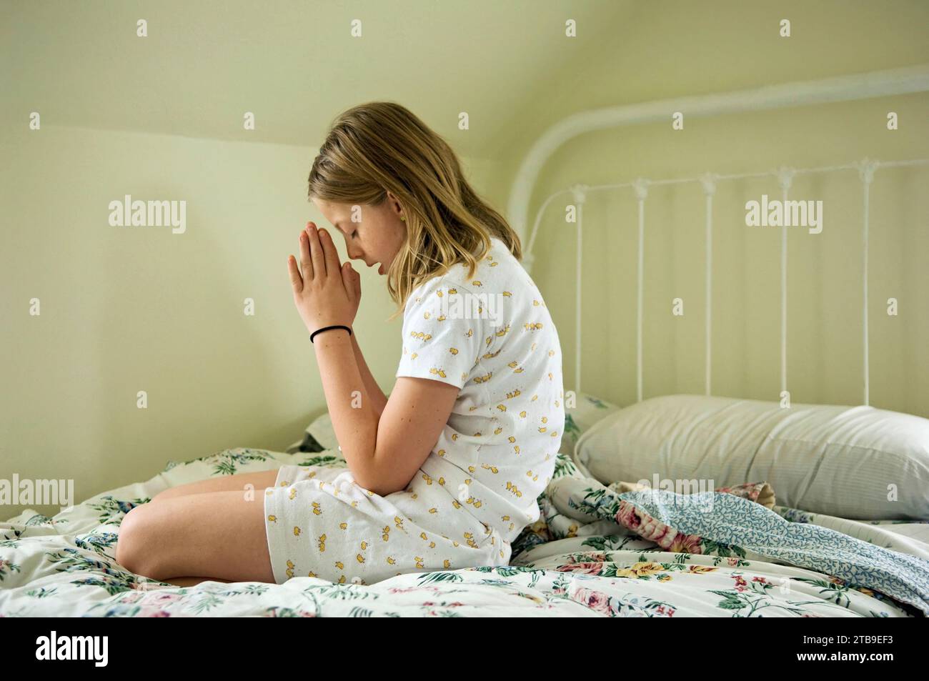 Preteen girl prays in her bedroom; Lincoln, Nebraska, United States of America Stock Photo
