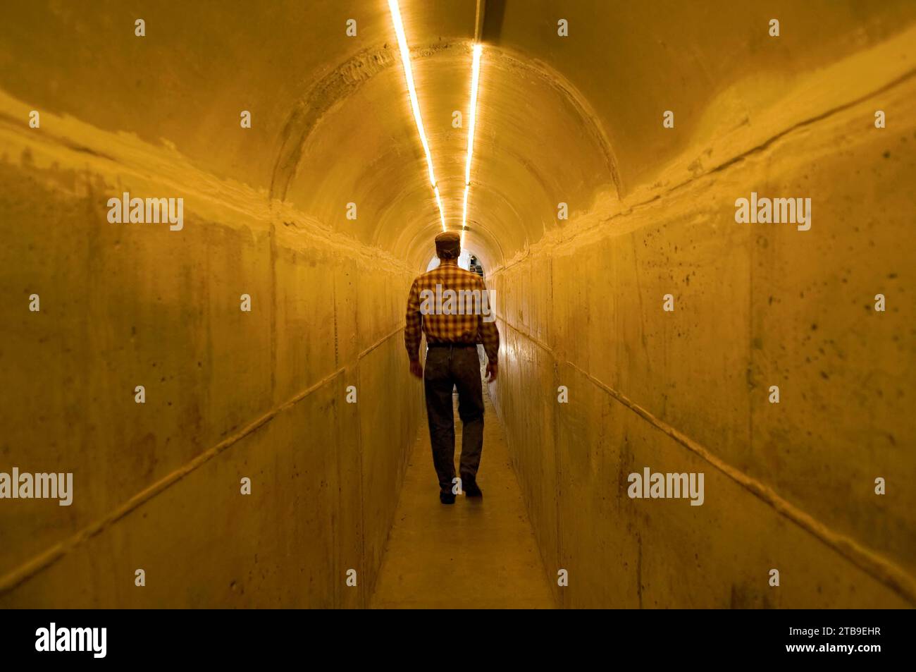 Man walks through a concrete tunnel leading to his garage; Lincoln, Nebraska, United States of America Stock Photo