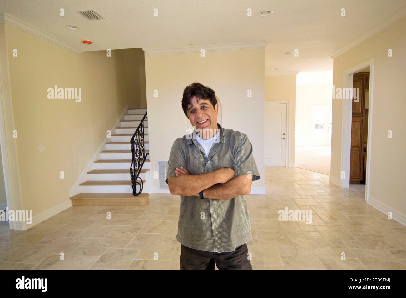 Man stands posing for the camera with arms crossed in a house with no furnishings; Tampa, Florida, United States of America Stock Photo